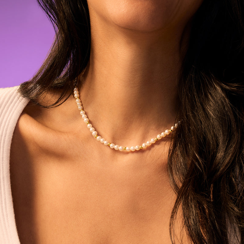 Cultured pearl bead necklace with 14kt yellow gold bead spacers near the neckline.