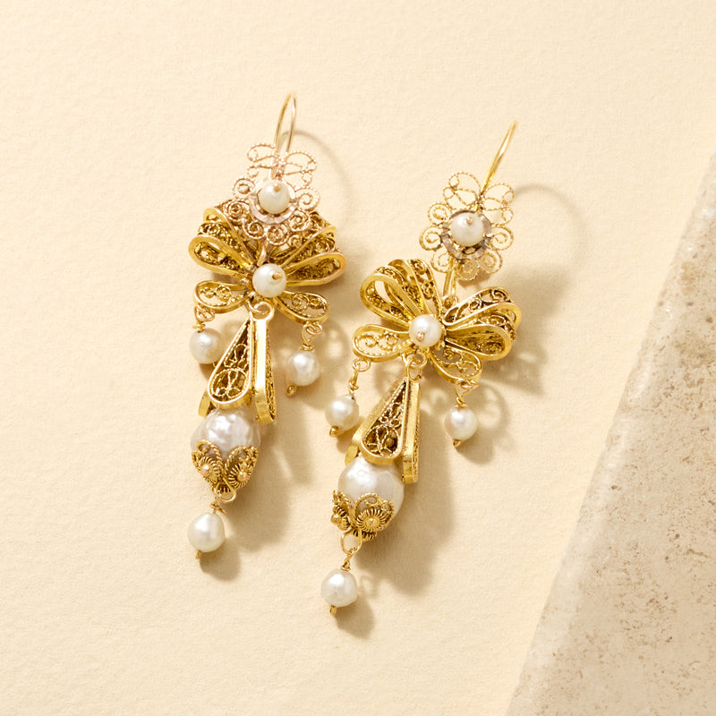 Close-up of 14kt yellow gold scroll drop earrings with white cultured pearls