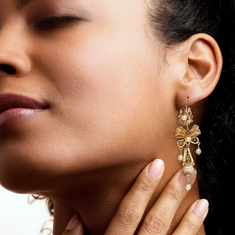 Model wearing 14kt yellow gold drop earrings with white cultured pearls and earwire