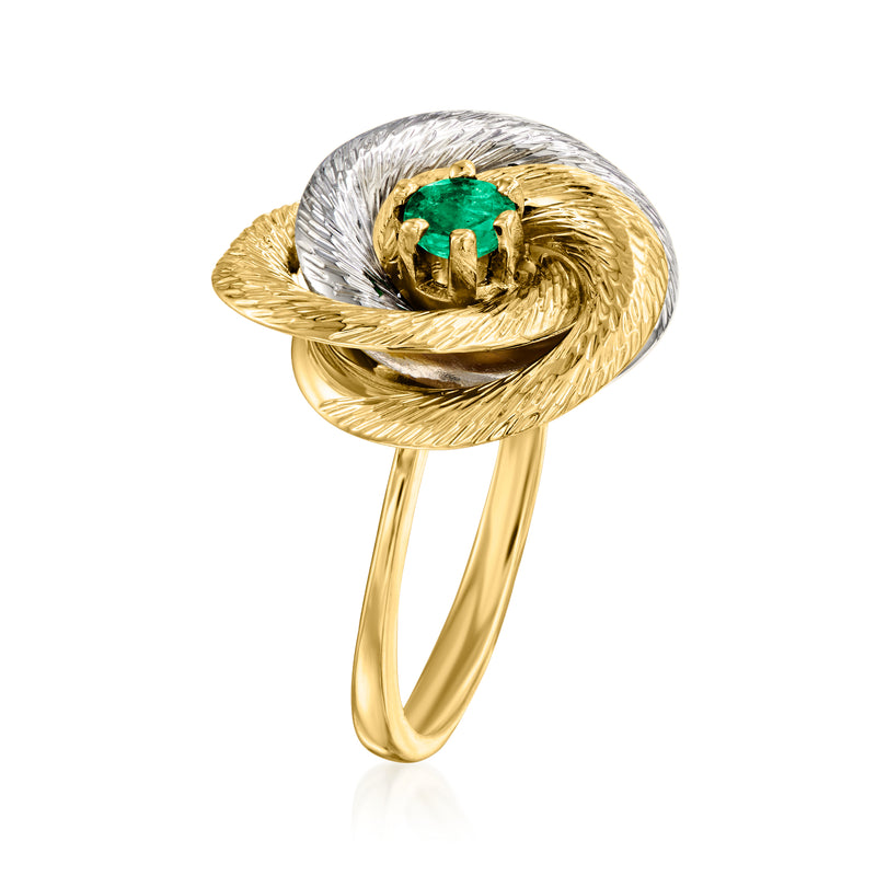 Two-tone gold knot ring with green emerald center stone, swirling oval band