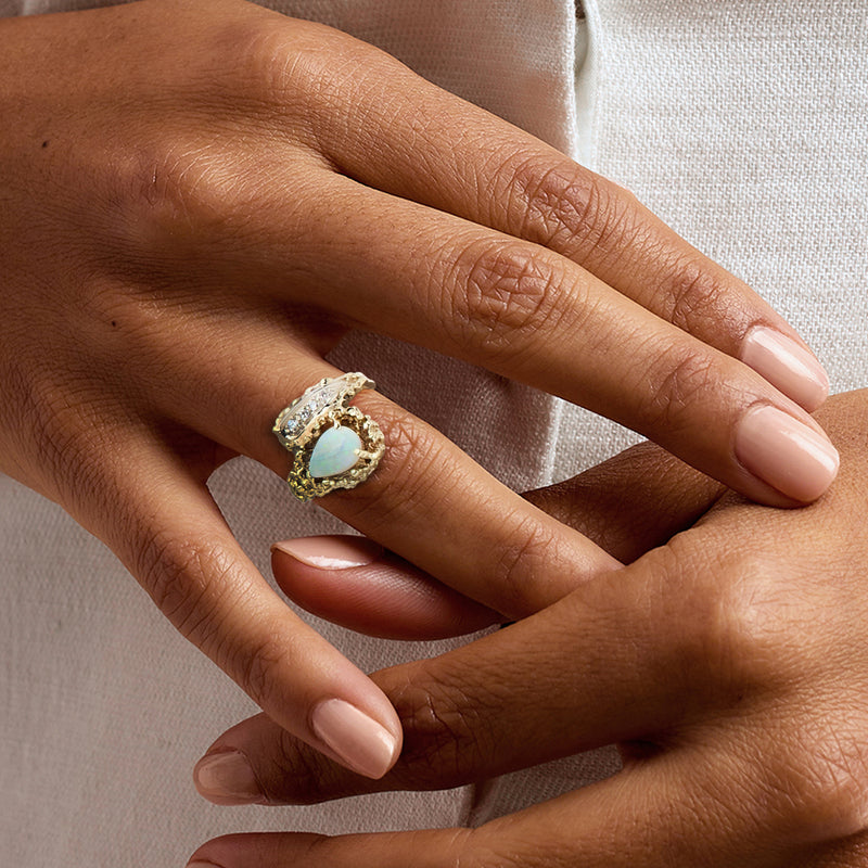 Opal and diamond bypass ring in 14kt yellow gold on hand, size 6