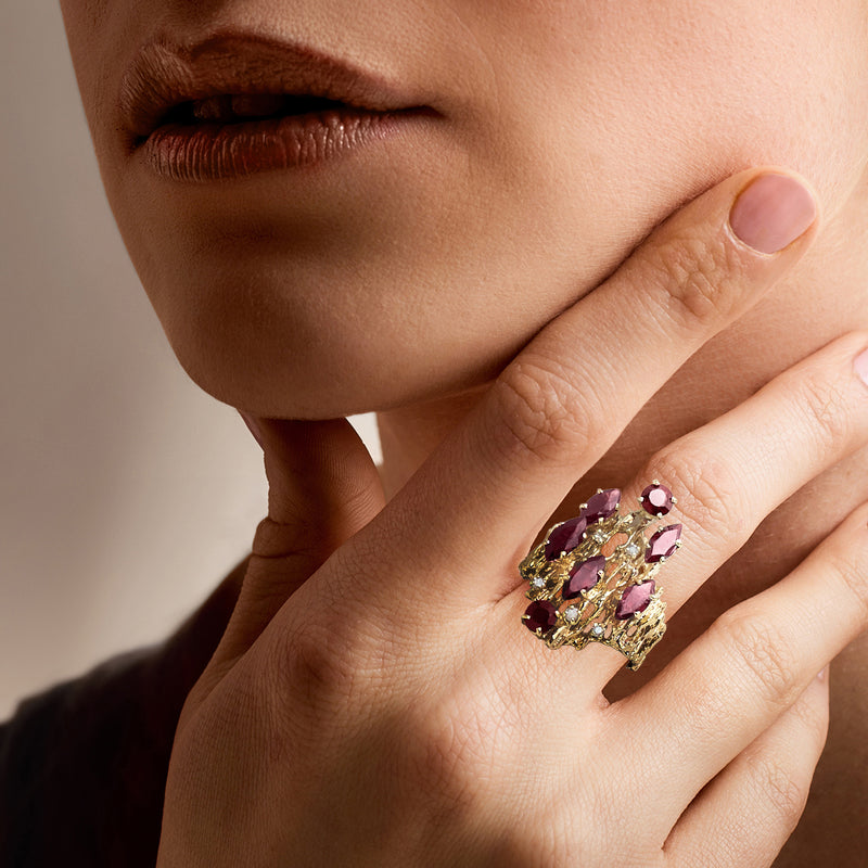 Yellow gold garnet and diamond ring worn on finger, close-up