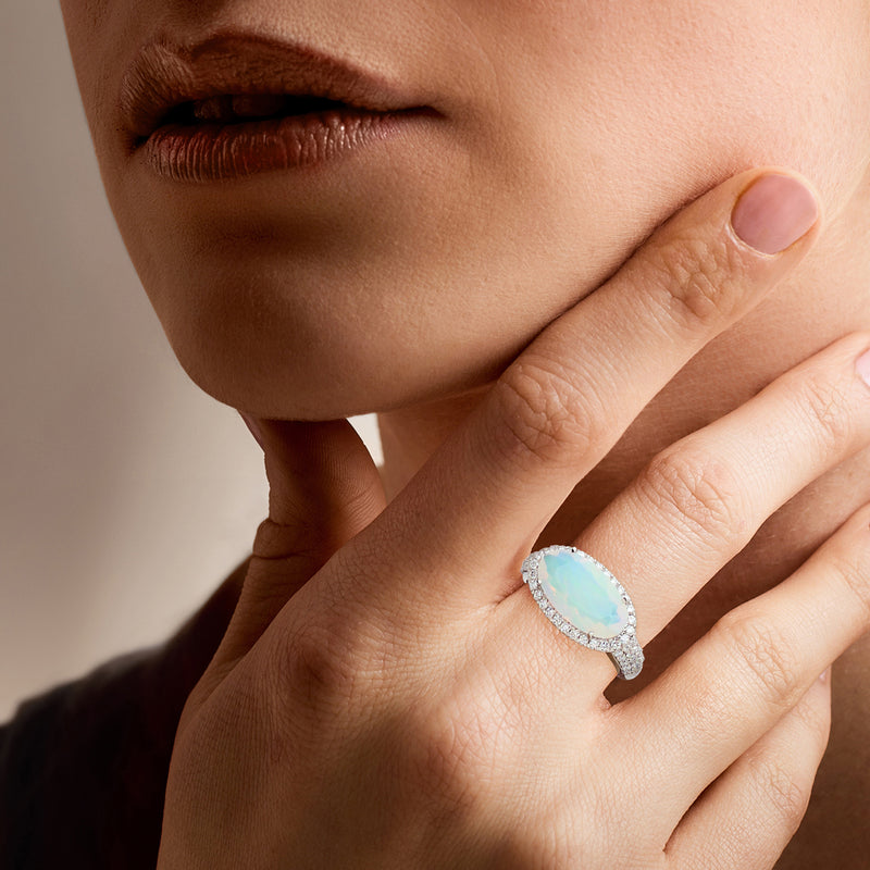 Platinum opal-like oval center ring with diamond halo worn on hand