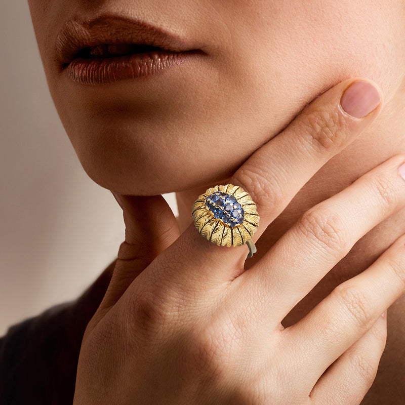 18kt yellow gold sapphire feather ring on hand, blue round gemstone cluster center