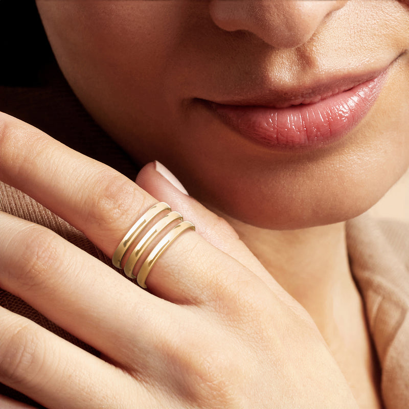 Three-row yellow gold stacking ring on finger, close-up
