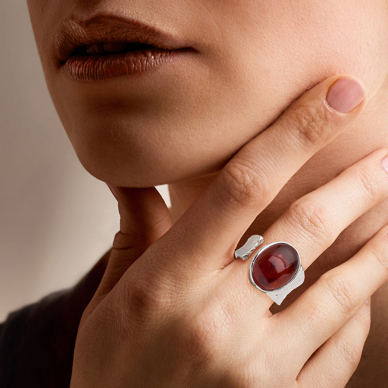Sterling silver oval cabochon open-wrap ring on hand, dark red stone