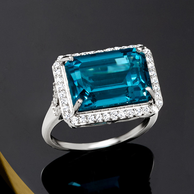 Close-up platinum ring with emerald-cut London blue topaz and surrounding diamonds