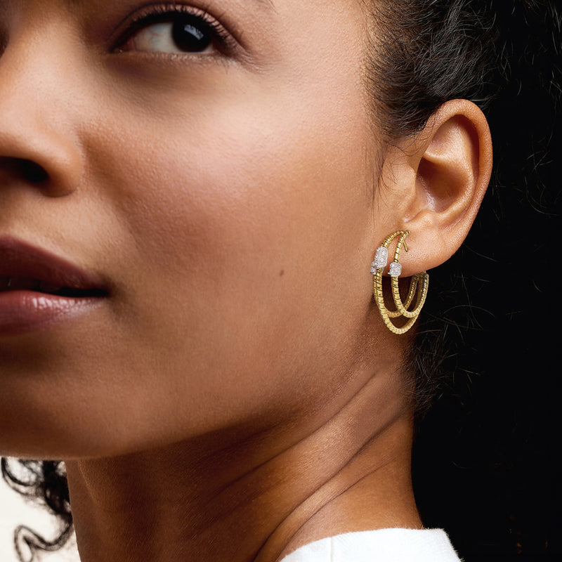 Close-up of triple-hoop diamond earrings in yellow gold on model ear