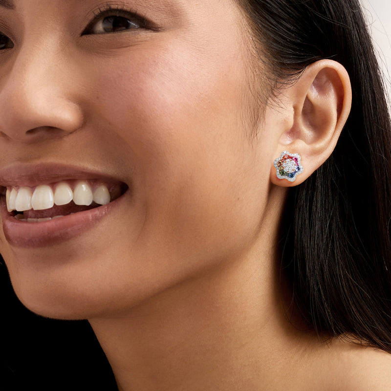Colorful sapphire and diamond flower stud earrings on ear, 18kt white gold posts