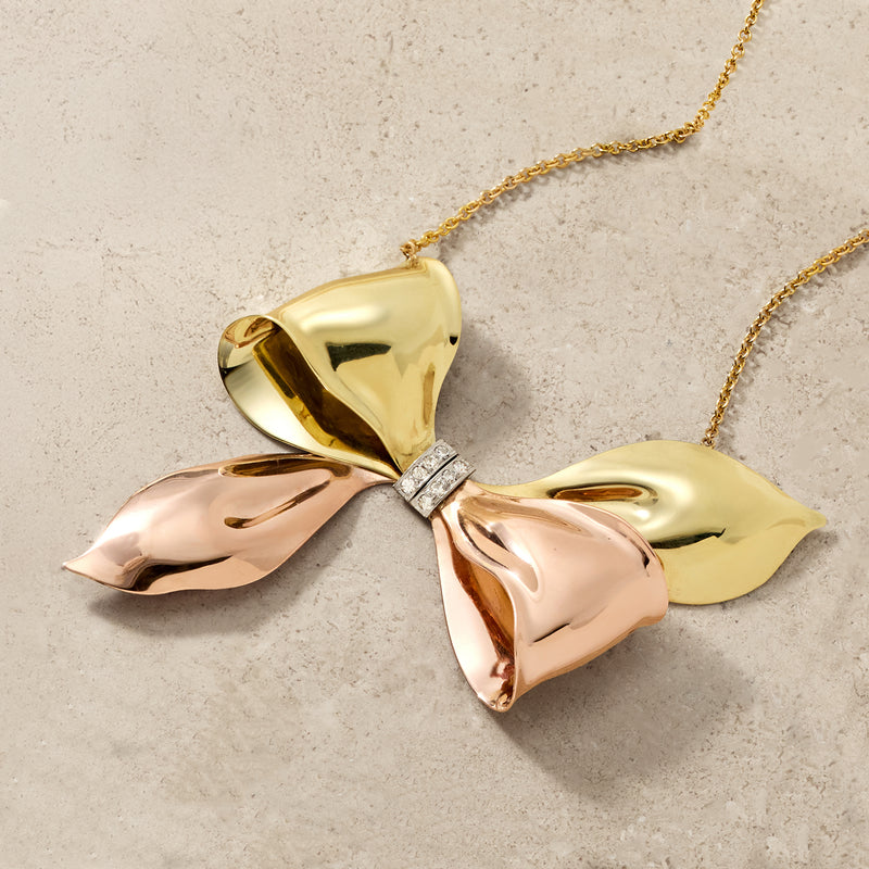 Two-tone gold bow pendant with diamond accent at center on chain