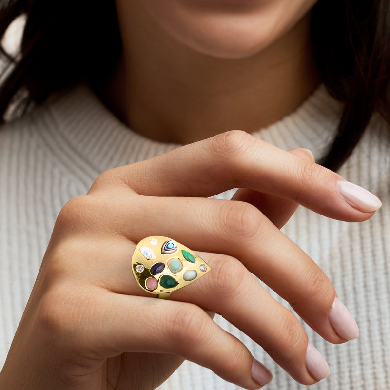 Gold teardrop gemstone ring on hand with multicolor stones and diamond accents