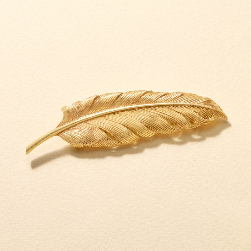Yellow gold feather brooch pin with curved quill shape and ribbed texture