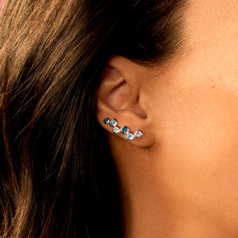 Sterling silver ear climber earrings with round blue topaz stones along the ear