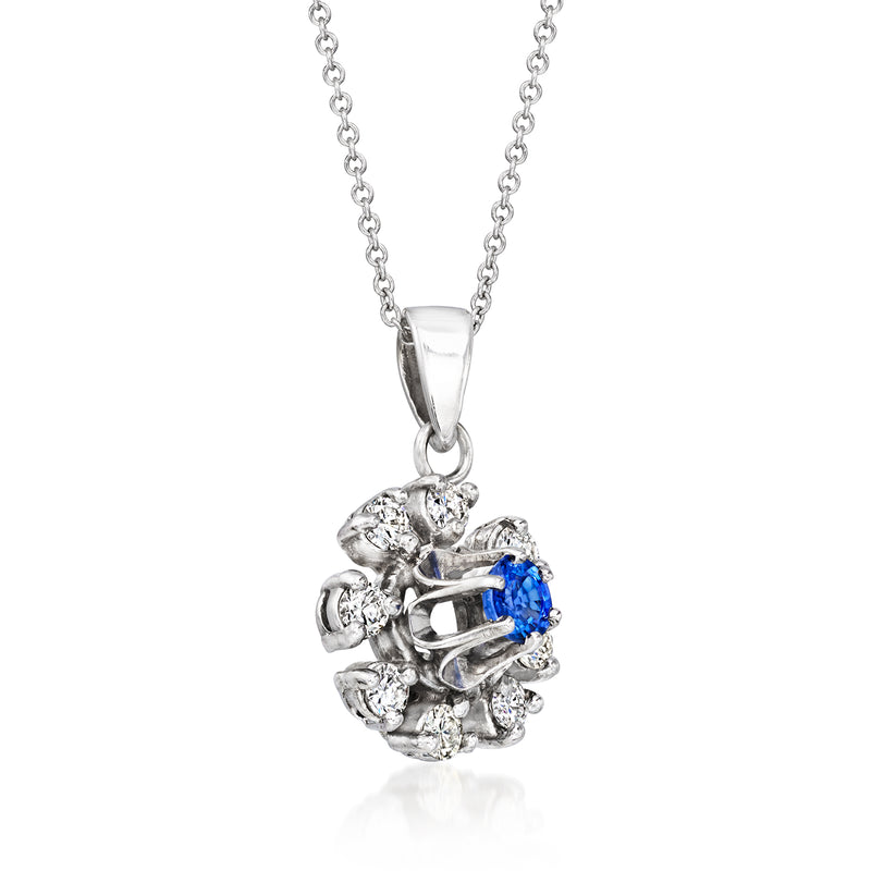 White gold sapphire pendant with prong-set blue stone surrounded by round diamonds