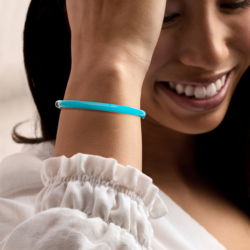 Turquoise enamel bangle bracelet worn on wrist, sterling silver openwork details.