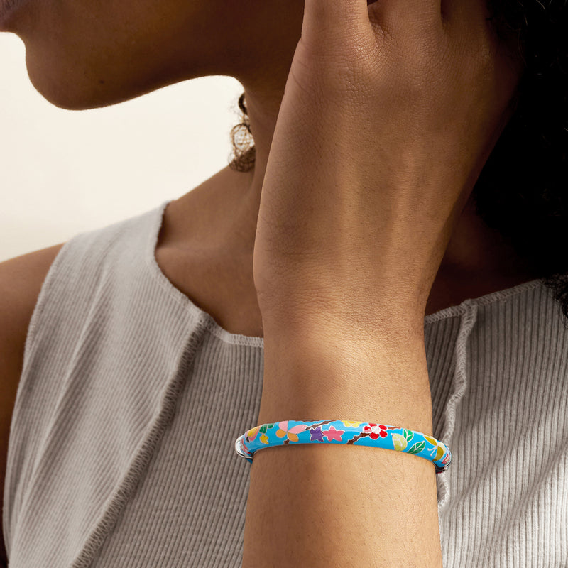 Multicolored enamel floral bangle bracelet in sterling silver, worn on wrist
