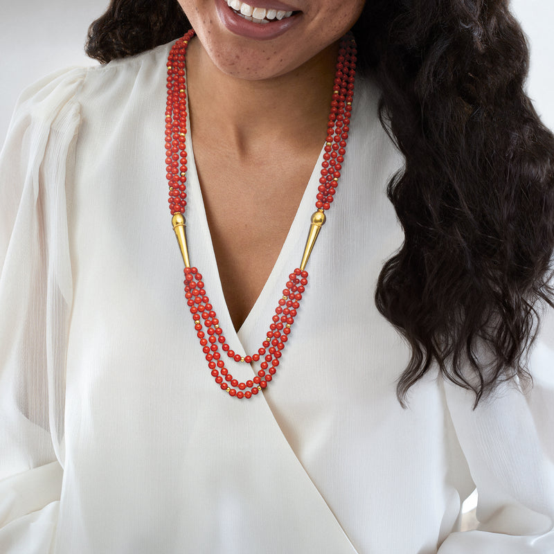 Red coral three-strand bead necklace with gold connector ends on model