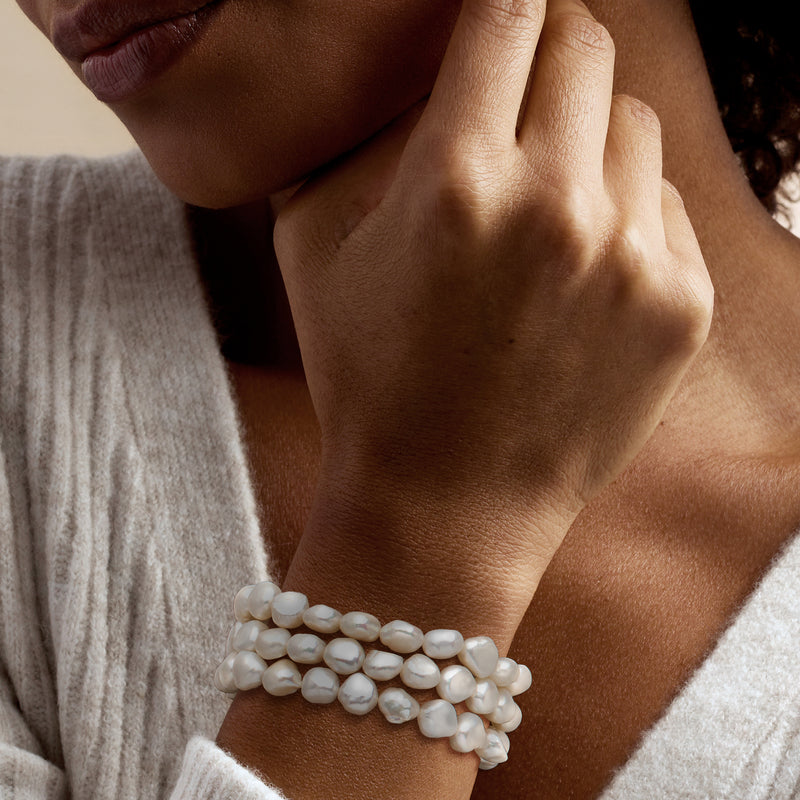Three-strand baroque pearl stretch bracelets on wrist with white pearls, stacked fit