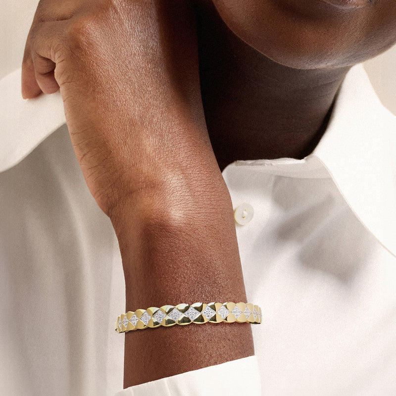 Gold CZ bangle worn on wrist, quilted pattern with white stone row accents