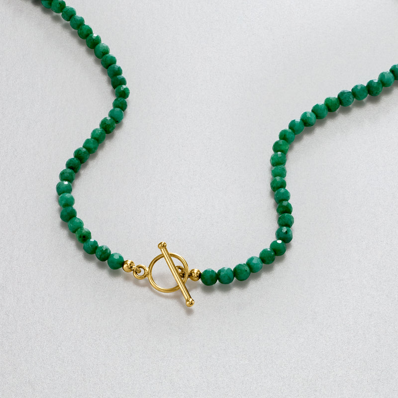 Close-up of emerald green bead necklace with gold toggle clasp
