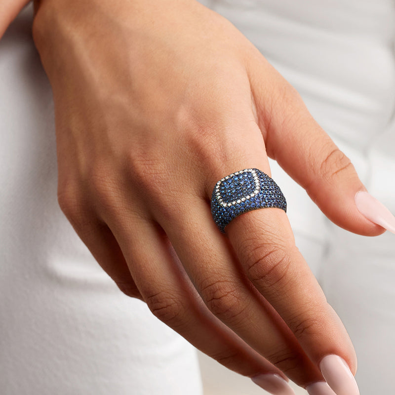 Sapphire and diamond dome ring worn on finger with blue clusters in white gold