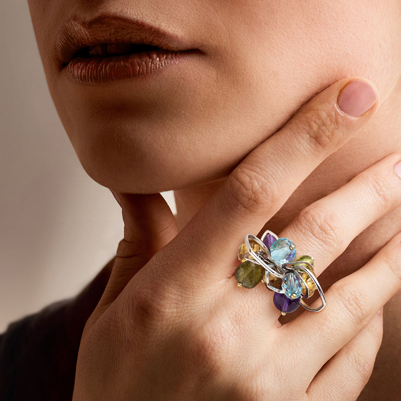 White gold heart multi-gem charm ring on hand with blue, purple, and green stones