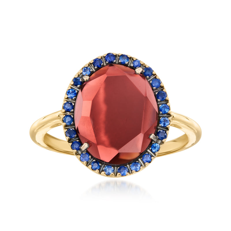 Oval red gemstone ring in 18kt yellow gold with blue sapphire halo and prong setting
