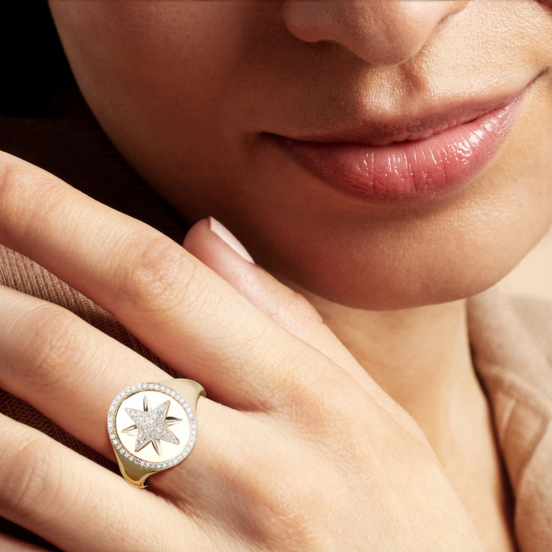 Diamond starburst signet ring on hand, set in yellow gold with round halo
