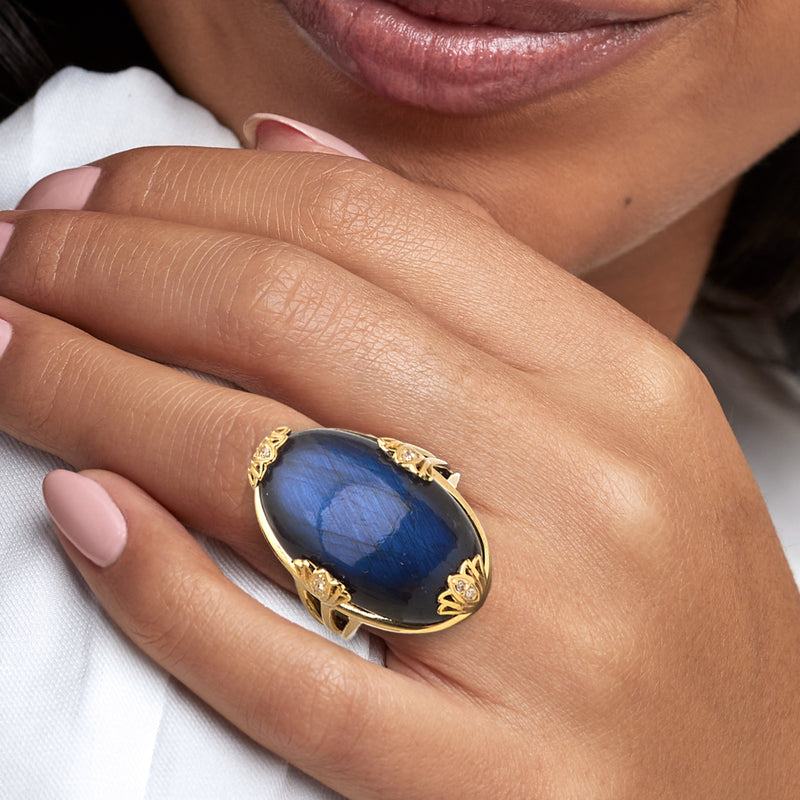 Labradorite lotus ring on hand: oval blue cabochon with gold-tone lotus setting