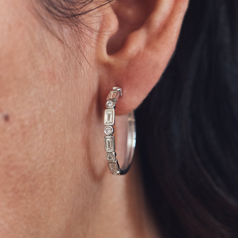 Sterling silver hoop earrings with baguette and round diamond stones, side view