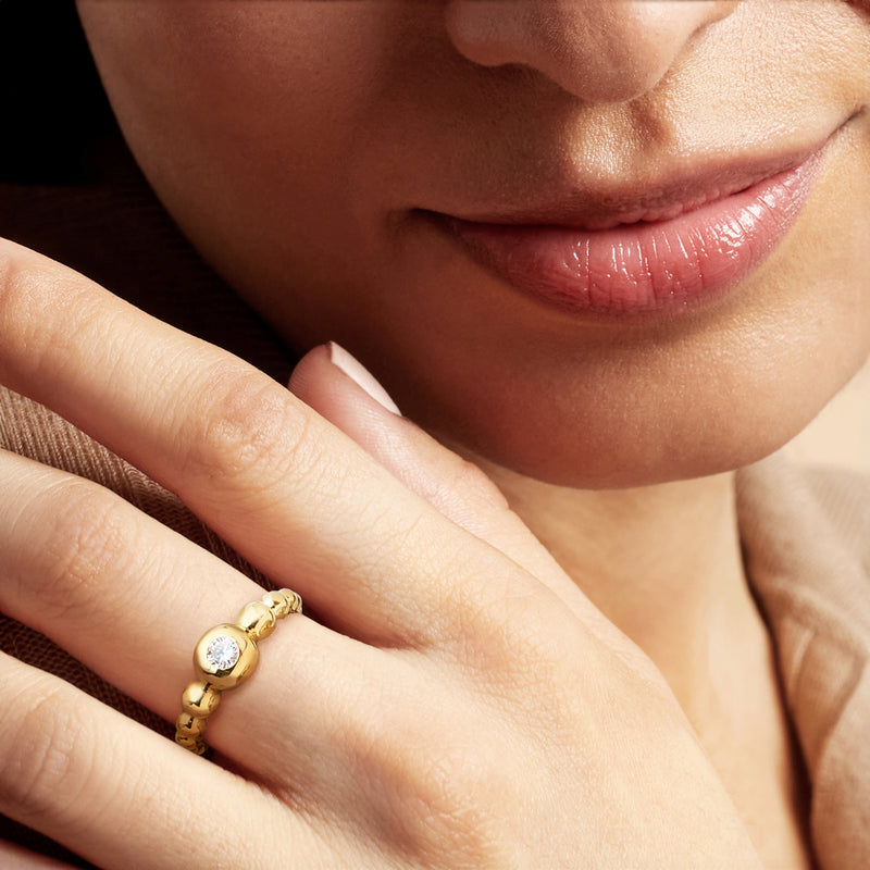 Gold bubble ring with round diamond on finger, close-up