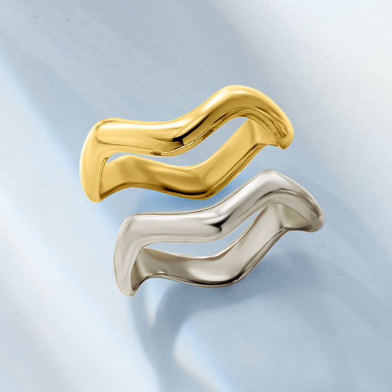 Two wavy stacked rings in gold and sterling silver, glossy curved reflective bands