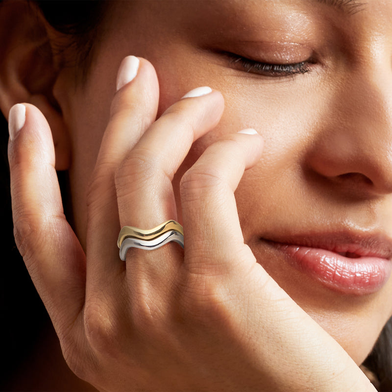 Wavy ring set on hand: gold and sterling silver curved bands with glossy shine