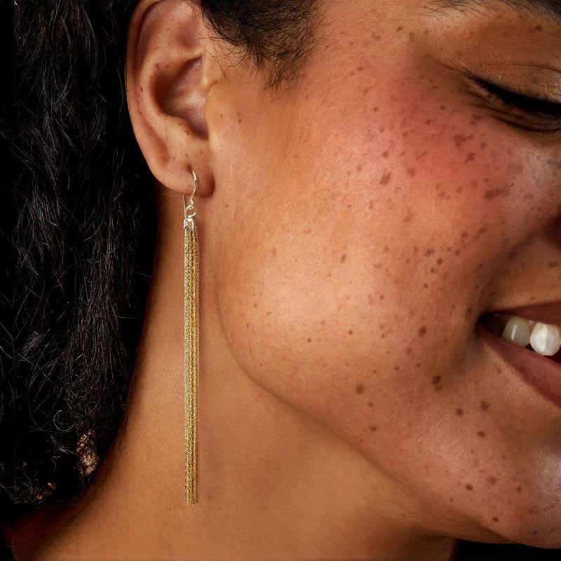 Worn two-tone gold tassel drop earrings on ear, long dangling fringes