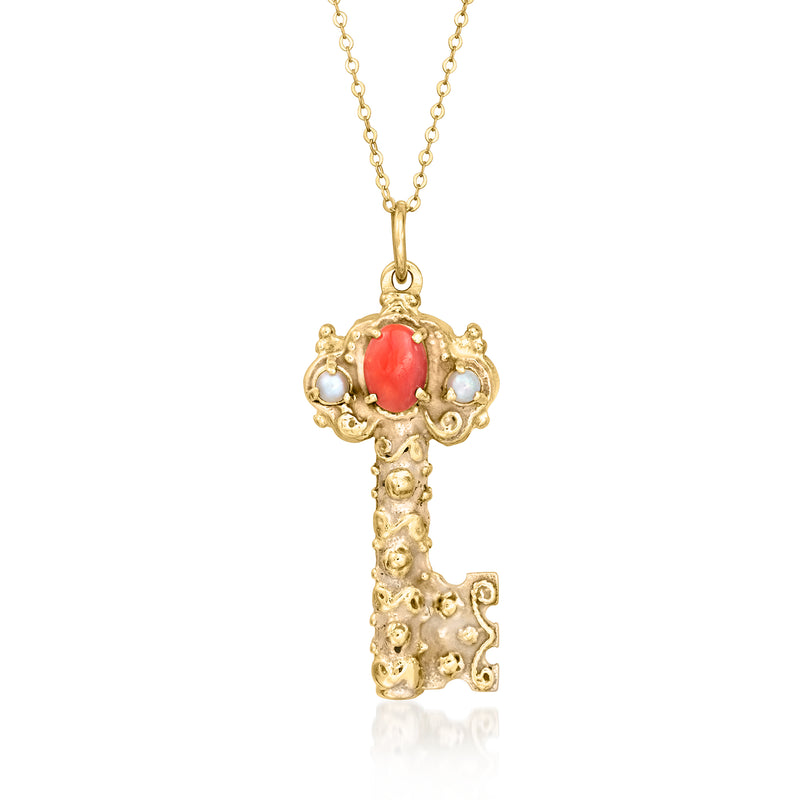 Gold key pendant necklace with coral-red oval center and small pearl-like accents