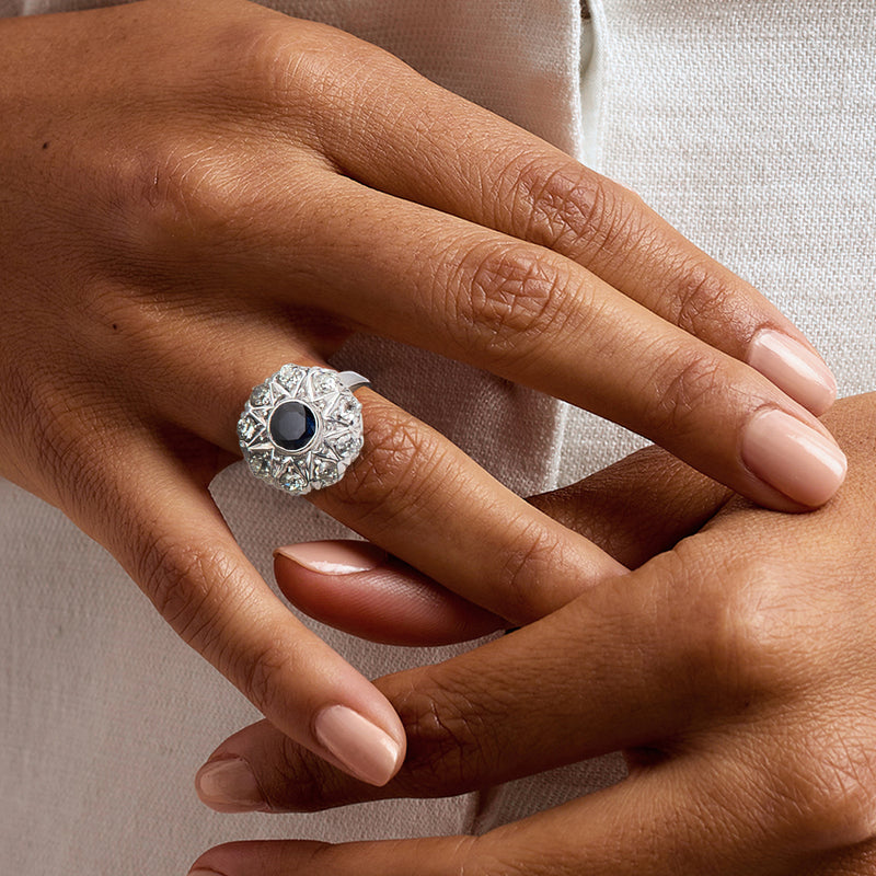 Vintage sapphire and diamond ring on hand, blue center stone with diamond halo setting