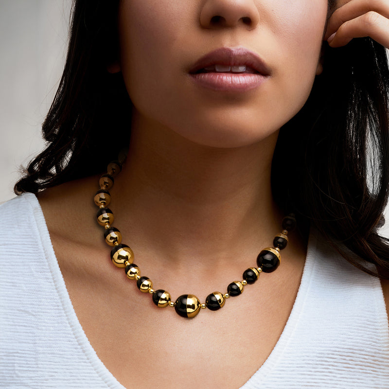 Gold-plated beaded necklace worn at collar with black agate rounds and gold accents