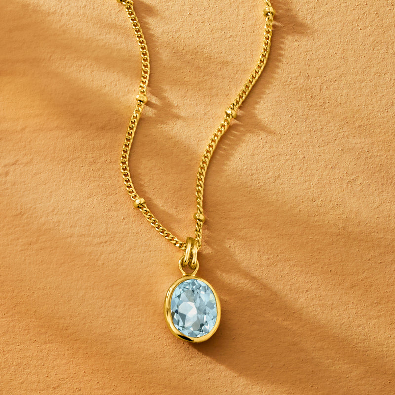 Gold-tone chain necklace featuring oval sky-blue topaz bezel pendant