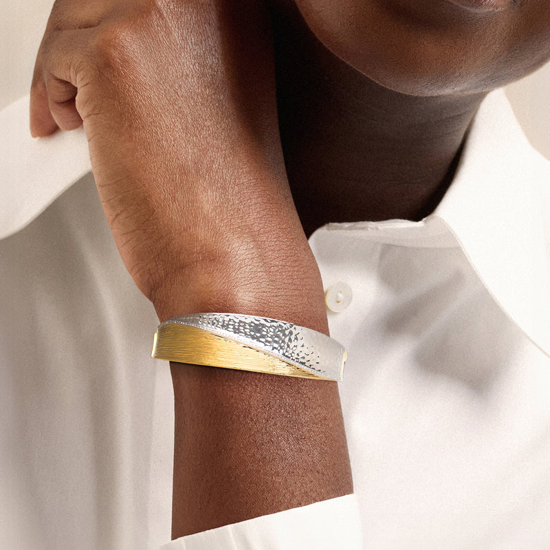 Two-tone textured bangle bracelet worn on wrist, gold-tone top and silver band