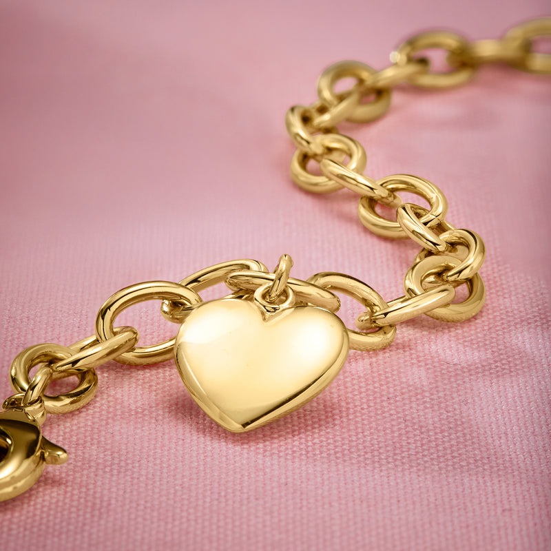 Close-up of gold-plated heart charm on a cable-chain bracelet with oval links