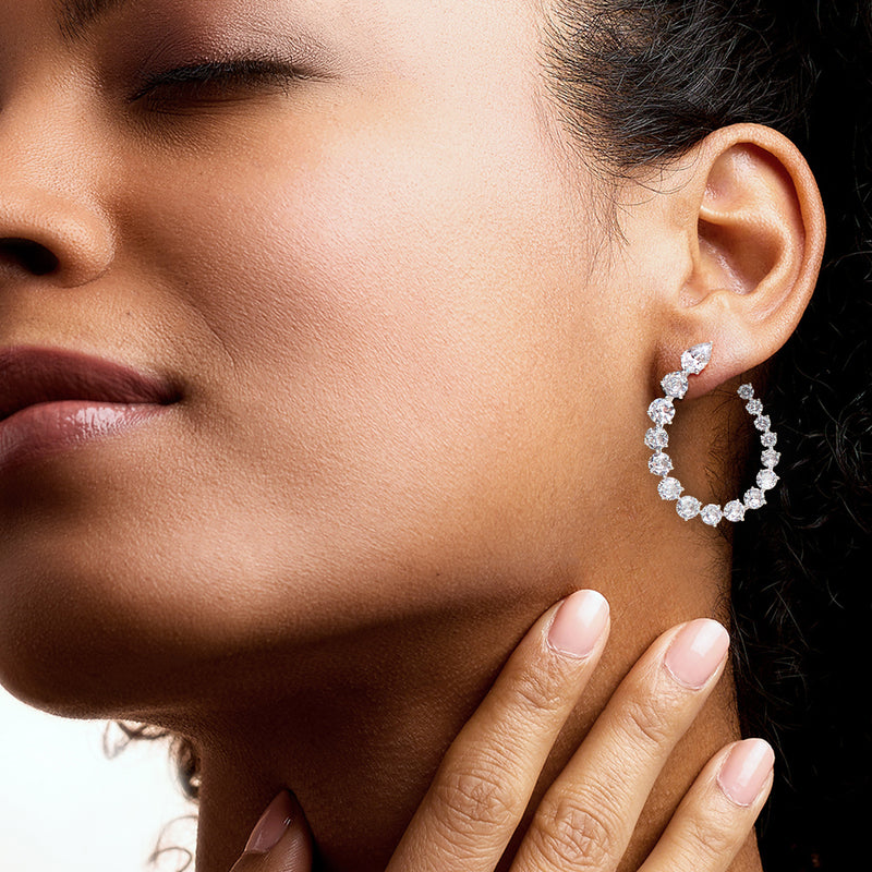 Rhodium-plated CZ hoop earrings on ear, round sparkling stones in an open hoop