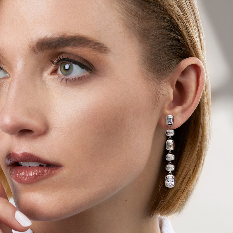 Rhodium-plated drop earrings with stacked square CZ stones, worn on ear