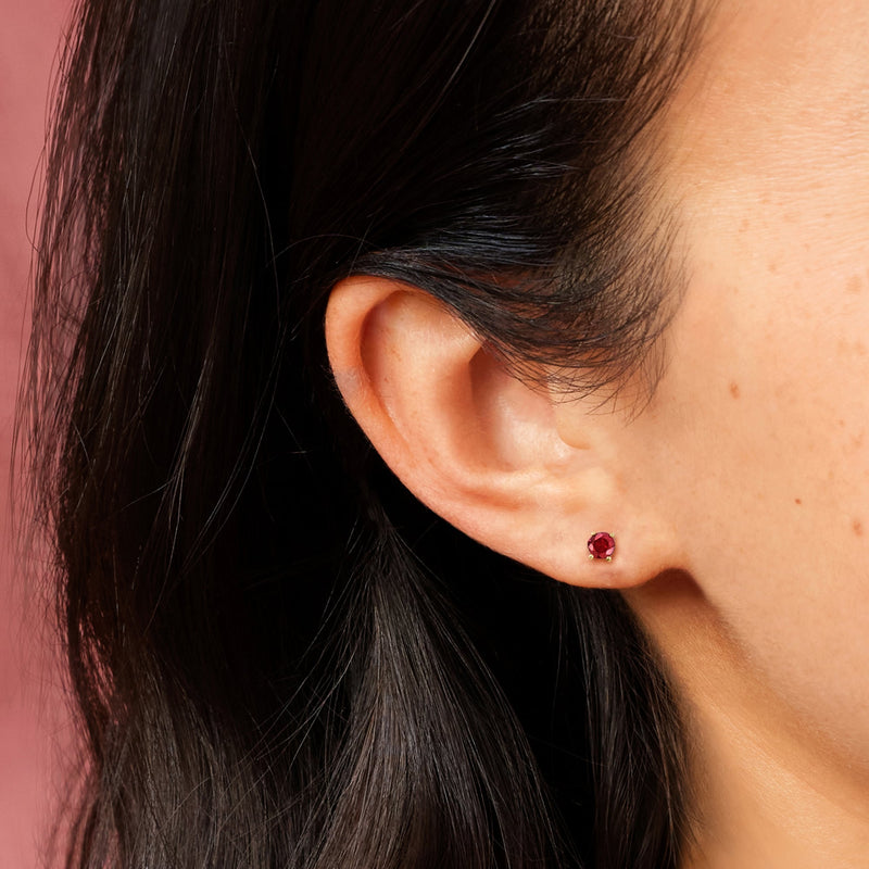 Close-up ruby stud earrings in 14kt yellow gold with small round red stone