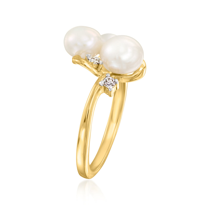 Gold ring featuring three white pearls with two small diamond cluster accents