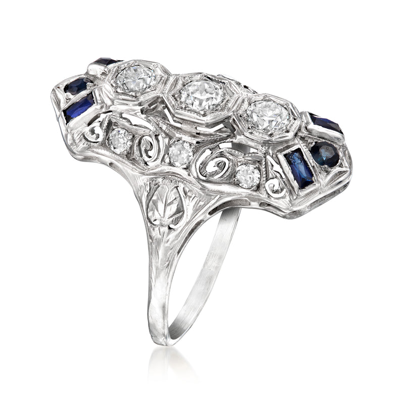 Ornate antique-style white gold ring with large center stone, clear side stones, blue accents
