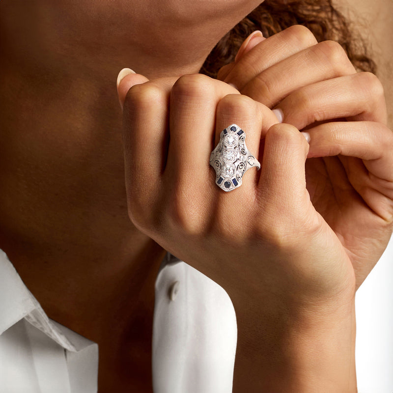 White gold statement ring with faceted center stone and blue sapphire details, on hand