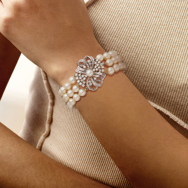 Cultured pearl and diamond flower bracelet on wrist with white gold clasp and pearl strands