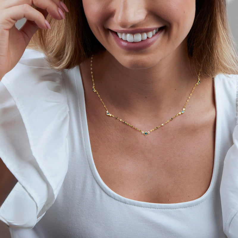 Gold station necklace worn at the neckline with London blue topaz stones
