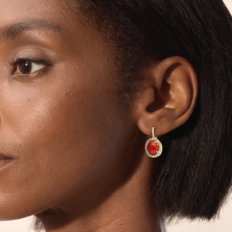 Diamond and coral red oval drop earrings on ear in 18kt yellow gold