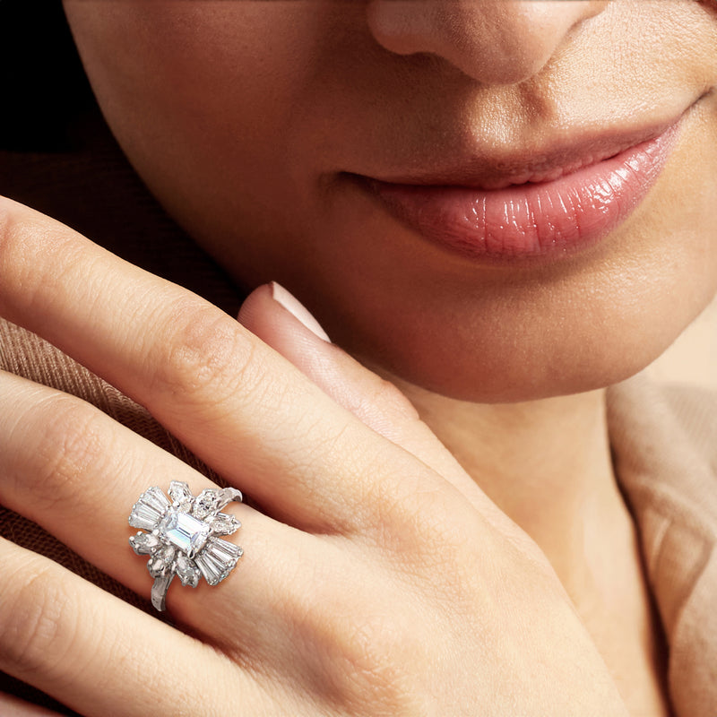 Diamond cluster ring on finger, emerald-cut center with baguette surround, white gold